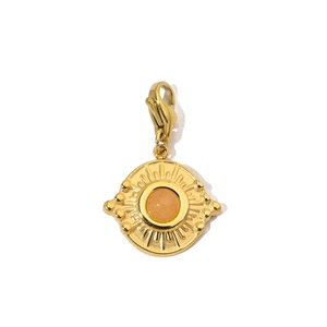 Detail of a vintage golden sunburst pendant with orange gemstone and lobster clasp