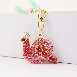 Cute golden snail keychain with pink rhinestones and lobster clasp on white box