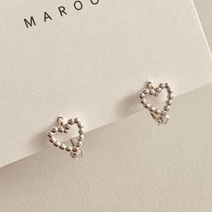 Macro shot of 925 sterling silver heart earrings with beaded texture on white card