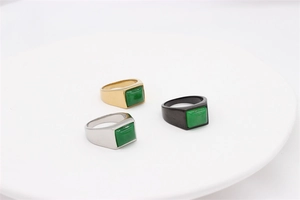 Detailed view of three emerald green stone rings in gold, silver, and black titanium steel