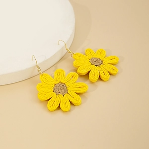 Détail de boucles d'oreilles tournesol tissées jaunes avec crochets dorés