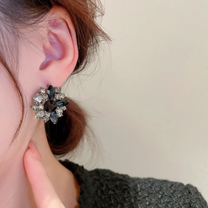 Close-up of model wearing floral earrings set with black and clear crystal rhinestones