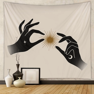 Detail of bohemian tapestry featuring hand silhouettes and solar icons on a beige wall