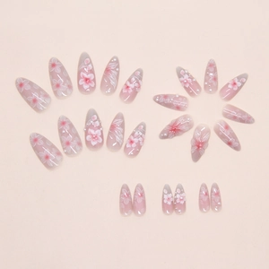 Detail of almond-shaped press-on nails with pink cherry blossom art and white pearls