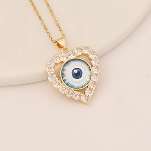 Close-up of gold heart pendant with pavé crystals and blue devil eye design on gold chain