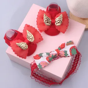 Detail of red baby socks and strawberry print headband set with lace bow and gold charm