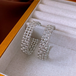 Detailed macro view of woven texture silver earrings set in a premium jewelry box