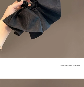 Detail of black pleated scrunchie with matte woven fabric texture and ruffled design