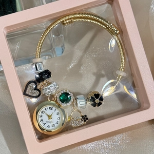 Close-up of gold beaded bracelet watch with heart charms in a pink gift box