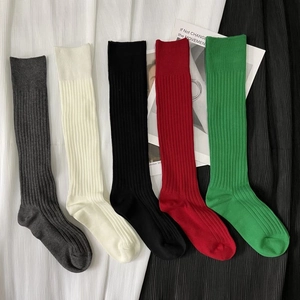 Flat lay of five pairs of ribbed knit long socks in grey, beige, black, red, and green