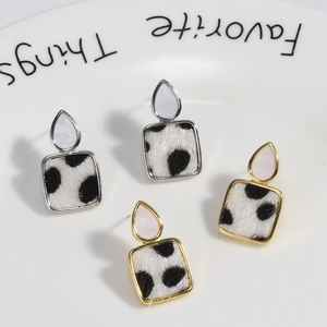 Leopard print faux fur earrings with gold and silver geometric metal frames on tray