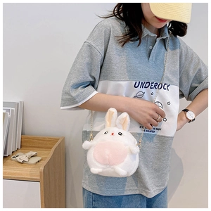 Detail of a plush bunny crossbody bag with pink ears and a golden chain strap