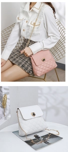 Close-up of heart-shaped metal lock and quilted embroidery on lady's chain bag