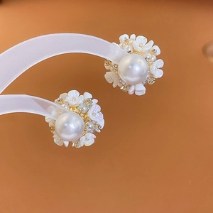 Détail de boucles d'oreilles fleur perle avec pétales blancs et zircons dorés élégants