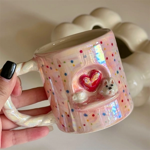 Detail of pink pearlescent ceramic mug with embossed puppy and red heart patterns