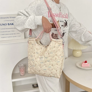 Vue détaillée du sac matelassé beige aux motifs d'ours avec bandoulière rose soyeuse