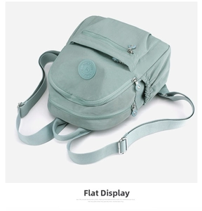Detail view of mint green waterproof nylon backpack with layered zipper pockets and side cords