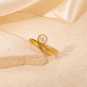 Macro detail of a golden snake ring with a white bead on a stone with satin fabric