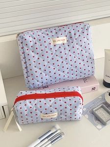 Detail of light blue quilted cosmetic bag set with red heart patterns and white labels