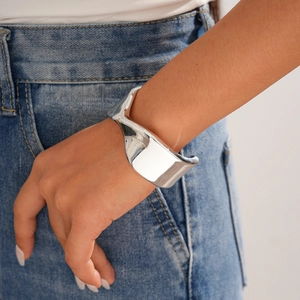 Close-up of a wide polished silver cuff bracelet with a modern geometric irregular shape