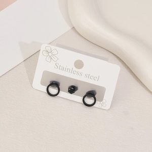Detailed macro view of minimalist black stainless steel stud earrings set on a display card
