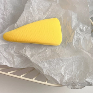 Detail shot of a yellow fabric triangle hair clip on white paper and mesh basket