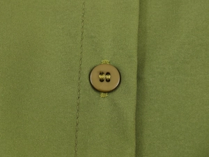 Close-up of olive green dress fabric texture with a polished dark brown resin button