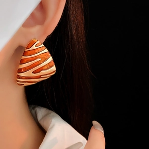 Detail of vintage gold plated triangular earring with brown zebra pattern on model