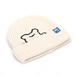 Close-up of bear embroidery and blue label on cream rib-knit beanie hat for winter
