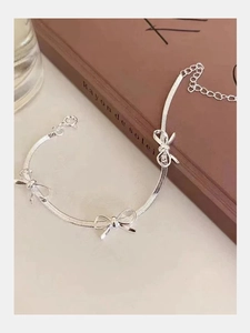 Detailed close-up of a silver bow knot bracelet featuring a flat snake chain design