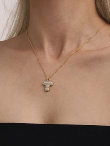 Close-up of golden T-shape pendant with pavé set zircons worn on female neck