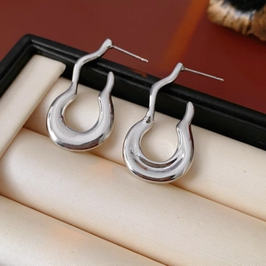 Macro shot of silver U-shaped streamlined earrings in a beige velvet jewelry box