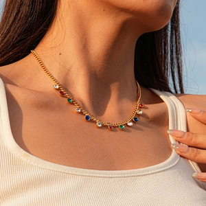 Detail of gold necklace with colorful round crystals on model in natural light