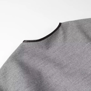 Detail of grey wool coat neckline with premium black leather trim and fine stitching