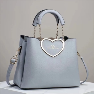 Close-up of light blue heart-shaped metal buckle on litchi texture leather handbag