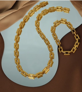 Detail of modern gold necklace and bracelet set with geometric links on a mirror