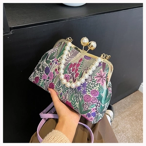 Detail einer floralen Jacquard-Handtasche mit Perlengriff und goldenem Metallverschluss