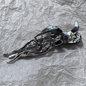 Macro shot of silver liquid metal hair claw clip with irregular flame streamline design