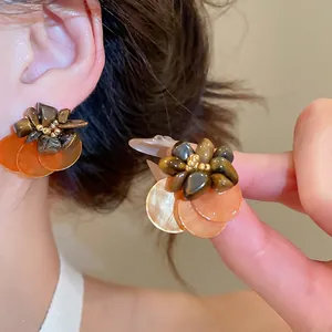 Retro tiger eye stone floral earrings with amber discs and gold beads on a model's ear