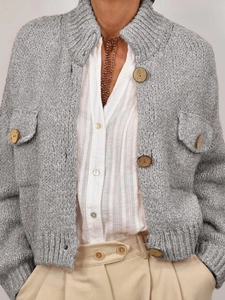 Close-up of silver-grey chunky knit cardigan featuring rustic wooden button detail