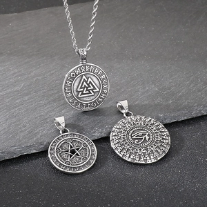 Detail of Viking Valknut and Eye of Horus pendants on a rustic dark slate background