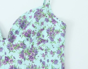 Detail of floral poplin dress showing blue fabric with purple flowers and strap stitching