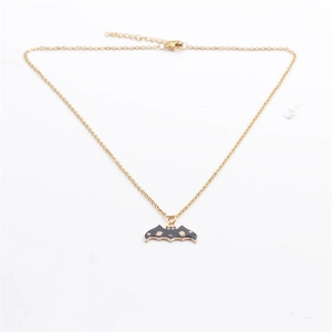 Détail du collier pendentif chauve-souris doré avec motifs étoiles et lune sur blanc