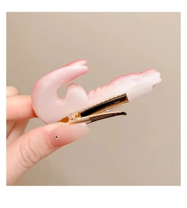 Detailopname van een realistische garnalen haarclip met roze verloop en gouden eendenbek