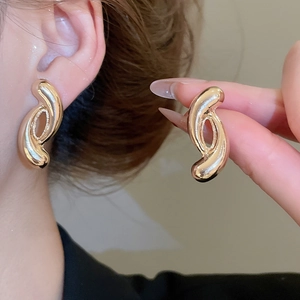 Detail view of twisted gold metal knot earrings on model showcasing elegant geometric curves