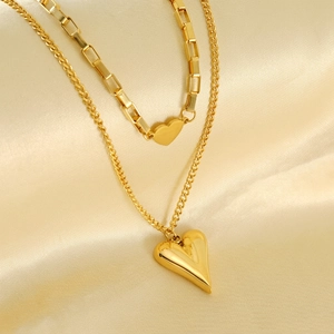 Double-layered gold stainless steel heart pendant necklace on champagne silk background