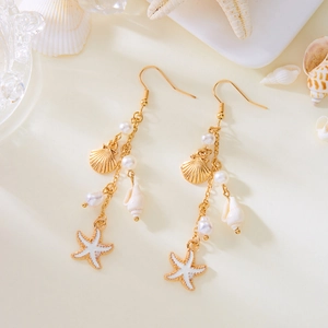 Detail of seashell and starfish charms with pearls on gold long tassel earrings