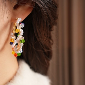 Detail view of colorful crystal bead earrings worn by a model in soft lighting