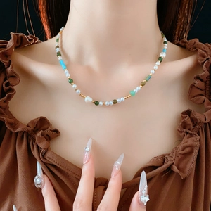 Close-up of beaded necklace with irregular pearls and green beads on a model