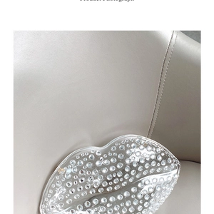 Macro shot of lip-shaped evening clutch bag with sparkling crystals on a leather chair